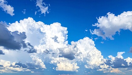 A vibrant blue sky filled with fluffy cumulus clouds, some tinged with shadow—evoking fair weather, atmospheric drama, and the poetic rhythm of skybound serenity.