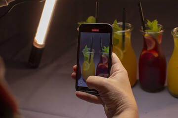A person captures beautiful photos of colorful drinks with a smartphone, showcasing various beverages