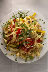 Penne pasta tossed with cherry tomato halves and chopped parsley, olive oil sheen, sliced chili for heat, bright lemon notes and rustic kitchen styling