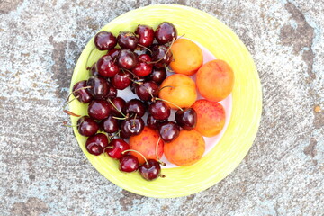 Sweet cherries and apricots on a plate.