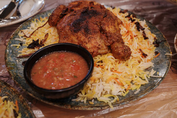A large plate of Middle Eastern chicken Mandi or Biryani rice with red sauce.
