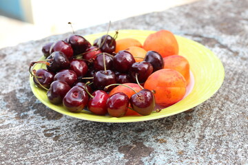 Sweet cherries and apricots on a plate.