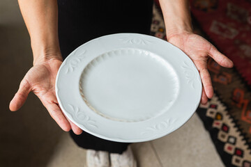 Hands holding empty white plate for mockup