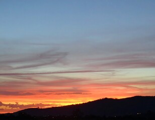 Obraz premium Sunset Over the Hills - A Colorful Evening Sky.