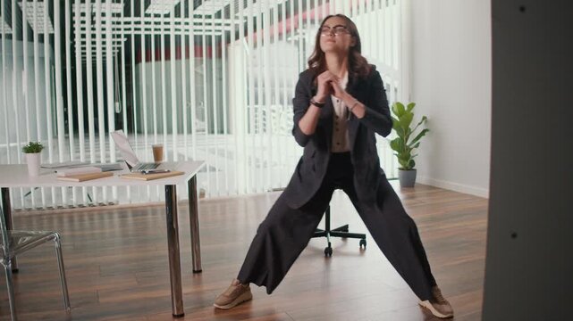 Office Ergonomics and Employee Wellness. Office Manager Performs Seated Side Leg and Lumbar Spine Stretch at Desk to Improve Flexibility, Support Posture, Reduce Discomfort and Promote a Balanced