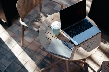 Cozy outdoor workspace with laptop and coffee during a sunny day