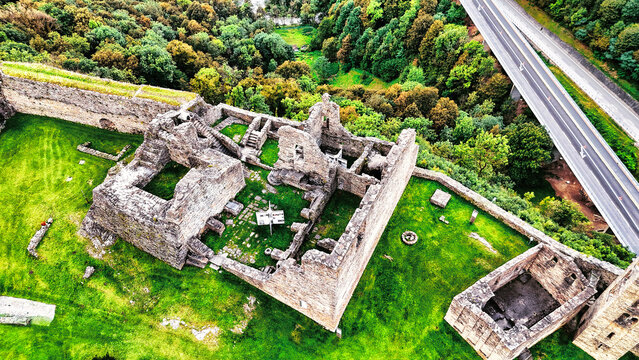 Aerial drone view of the Mesocco Castle ruins (Castello di Mesocco) in Grisons, Switzerland, a medieval site contrasting with the modern highway.