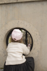 Little child exploring beyond circular frame, Toddler peering at natural scenery through circular aperture