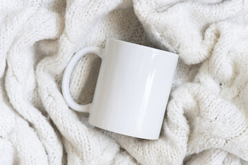 White blank coffee mug on red knitted sweater top view, Christmas winter Holiday mockup