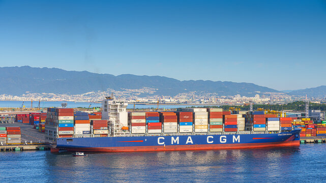 Osaka, Japan - Oct 11 2024, panoramic sea view of the docks of the Osaka Commercial Port with a heavily loaded CMA CGM cargo ship moored during the daytime, Osaka, Japan