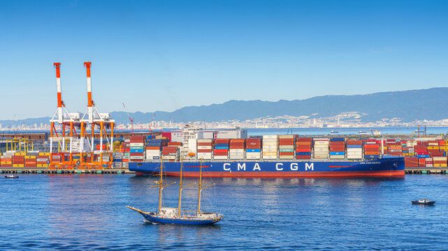 Osaka, Japan - Oct 11 2024, panoramic sea view of the docks of the Osaka Commercial Port with a heavily loaded CMA CGM cargo ship moored during the daytime, Osaka, Japan
