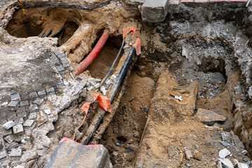 Deep Trench Revealing Underground Utility Pipes in City.