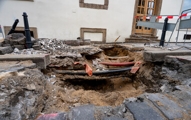 Deep Trench Revealing Underground Utility Pipes in City.