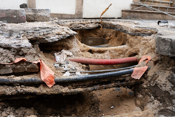Deep Trench Revealing Underground Utility Pipes in City.
