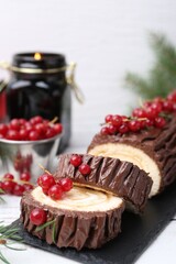 Delicious Yule log (traditional Christmas cake) with redcurrant on light table, closeup