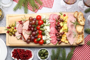 Delicious Christmas Charcuterie board with snacks and fir branches on grey textured table, flat lay