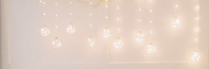 Christmas decorative branch with glowing light bulbs hanging on wall. Festive home interior...