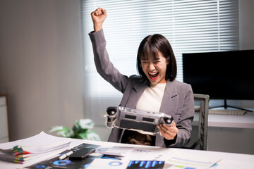 Asian businesswoman celebrating victory playing mobile game in office