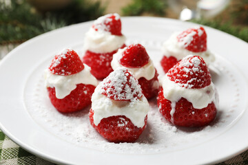 Christmas food. Santa hats made of strawberries and whipped cream on table, closeup