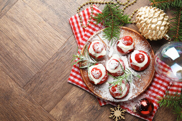Christmas food. Santa hats made of strawberries, whipped cream, rosemary and decor on wooden table, flat lay. Space for text