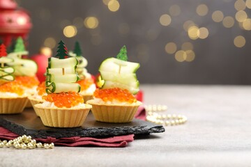 Tasty tartlets on grey textured table against blurred lights, closeup with space for text. Christmas appetizer
