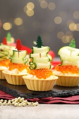 Tasty tartlets on grey textured table against blurred lights, closeup. Christmas appetizer