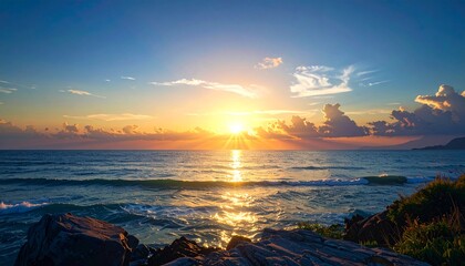 Golden sunset over tranquil ocean waters, brilliant sunbeams illuminating gentle waves and rugged coastal rocks. A serene, breathtaking natural seascape at dusk