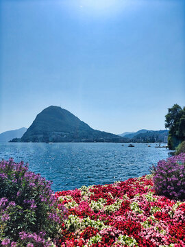 View of Monte San Salvatore and Lake Lugano from Parco Ciani, Ticino, Switzerland, with colorful flower beds in spring/summer.