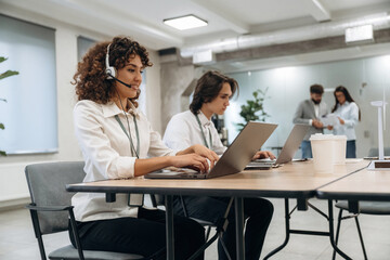 Obraz premium Call center, woman is in headphones. Group of people are working in the office together as a team