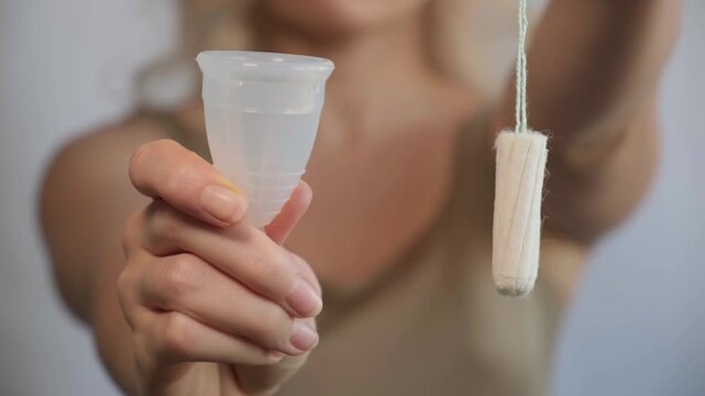 Close-up woman shows menstrual cup in hand. Feminine hygiene products, environmental responsibility and self-awareness. Daily care and the female cycle. Eco in women health, menstruation or period