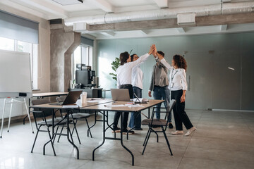 Celebrating, doing high five. Group of people are working in the office together as a team