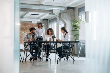 Unfinished room, brick wall. Group of people are working in the office together as a team