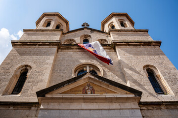The domes and bell towers of the Orthodox Church of St. Nicholas rise above Kotor Old Town under a bright sky, showcasing its Byzantine architecture.