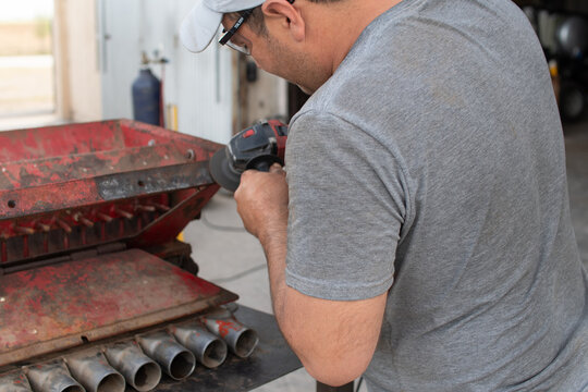 Operario lijando una estructura de hierro, reparando con anteojos protectores, primer plano