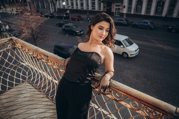 Woman in black posing with city street view from balcony