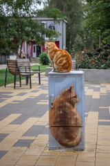 a ginger cat sits on a pedestal with a ginger cat painted on it