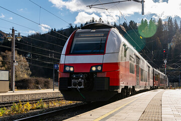 Modern Red and White Passenger Train at Railway Station in Mountain Landscape