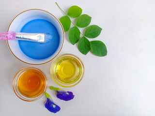 Butterfly pea or bunga telang face mask ingredients with blue liquid, brush, honey, and olive oil. Natural skincare and beauty concept.