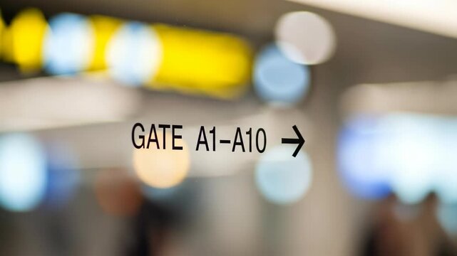 A blurred image of an airport sign showing the directions to gate A1 through A10, symbolizing travel and movement in an international setting.