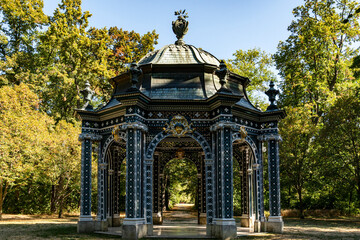Ornate Historic Pavilion with Intricate Metal Architecture Surrounded by Trees in Sunlit Park