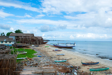 Traditional Wooden Boat Under Construction on Tropical Beach with Palm Trees, Clear Blue Sky, and Turquoise Sea in Remote Coastal Setting