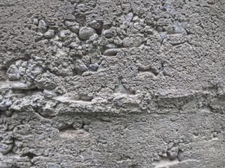 Rough plastered wall texture background with exposed gravel stones