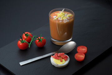 Vaso de salmorejo con tomate huevo duro jamon con fondo oscuro