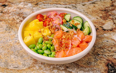 Fresh sushi bowl with salmon, pineapple, and vegetables on a marble surface