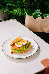 Delicious croissant sandwich with fresh ingredients on a white plate