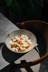 Fresh salad with vegetables and herbs served in a bowl on a table