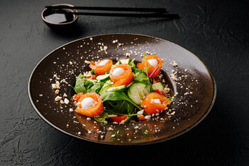 Delicious salmon salad served on a dark plate with chopsticks nearby