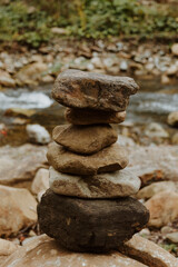 Balancing tower of stones on the bank of a mountain river symbolizing harmony, balance, mindfulness, and relaxation in nature. Concept of meditation and peaceful outdoor lifestyle.