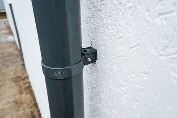 inspecting stained gray downspout exterior, closeup of stained gray downspout on textured wall,...