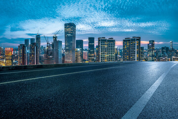 Elevated view from an empty asphalt road of the modern city skyline and central business district at dusk.